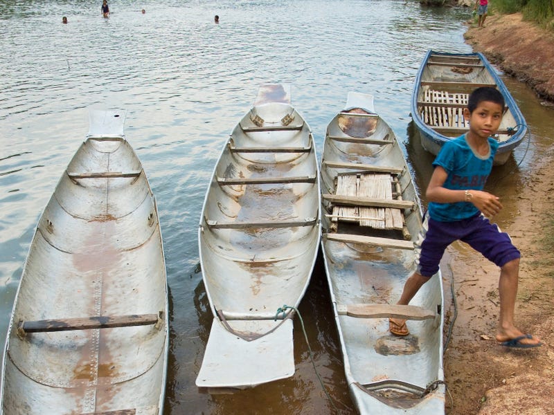 A boy hops out of a canoe made from fuel tanks dropped by US bombers during the Vietnam War
